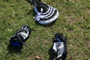 Lacrosse stick and gloves on turf