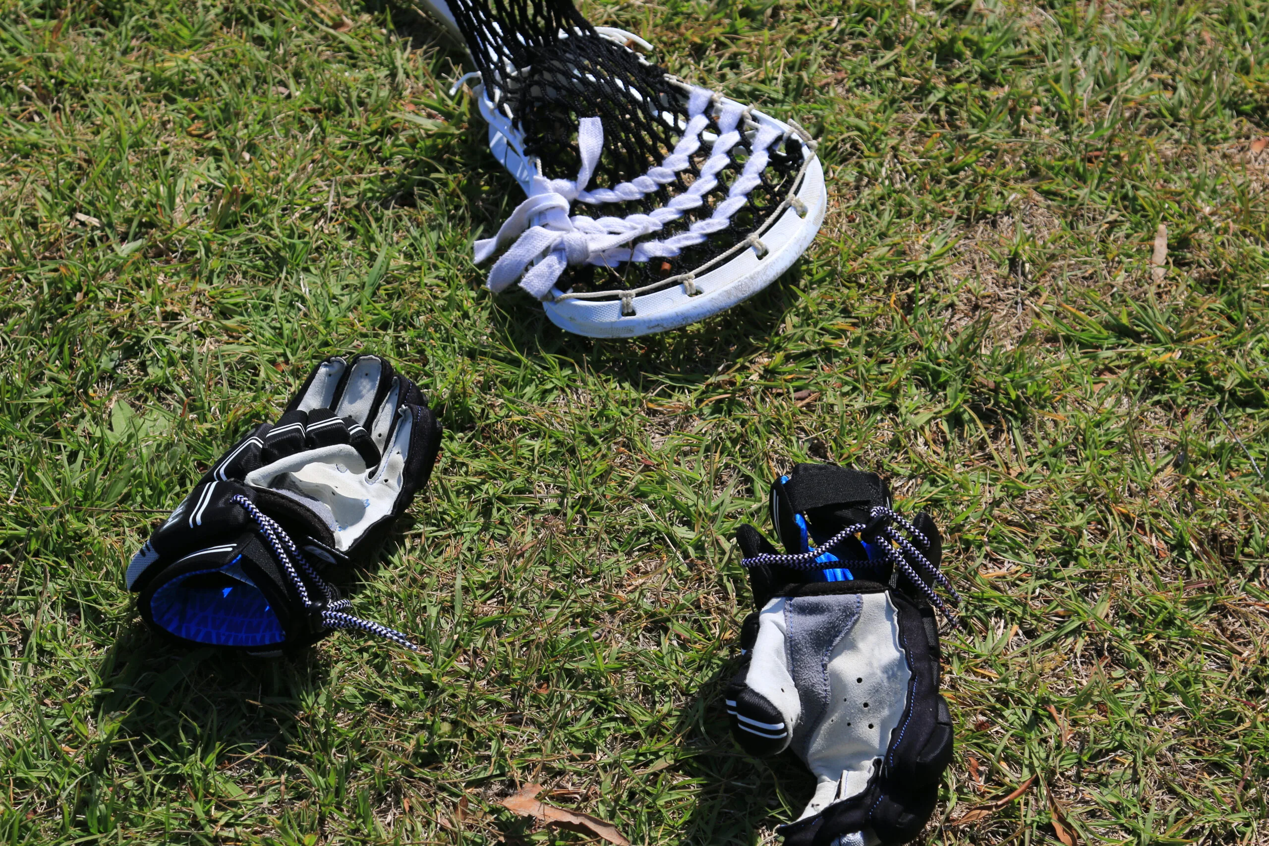 Lacrosse stick and gloves on turf