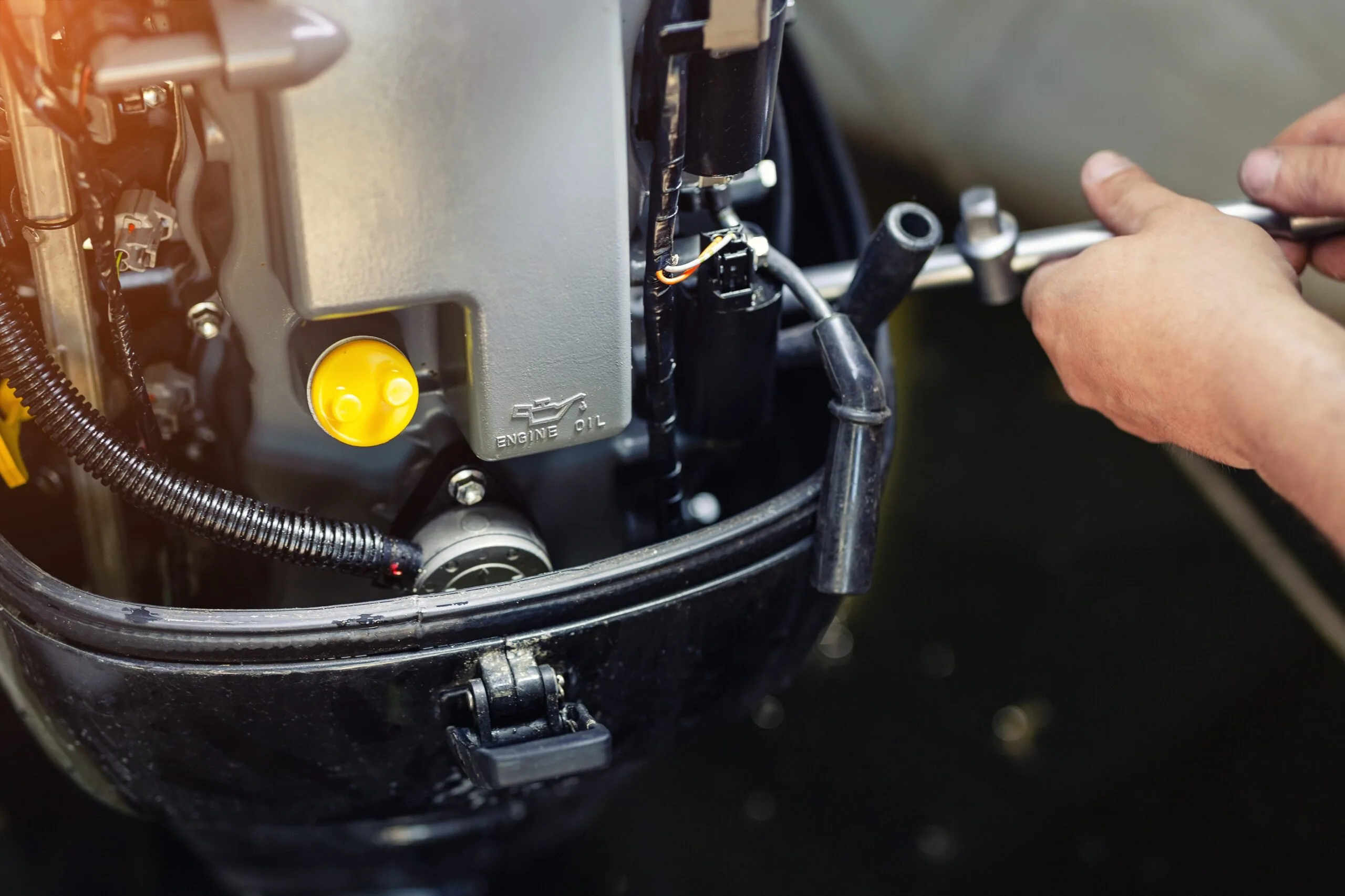 Hands using a tool to service an outboard boat engine.