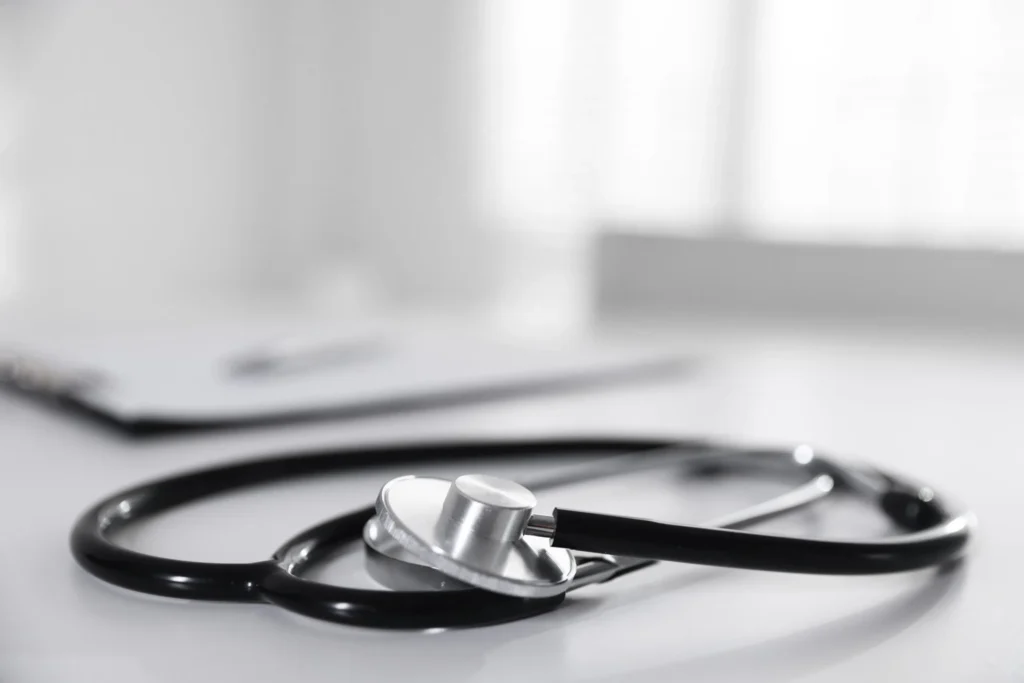 Stethoscope and paperwork on a white desk.