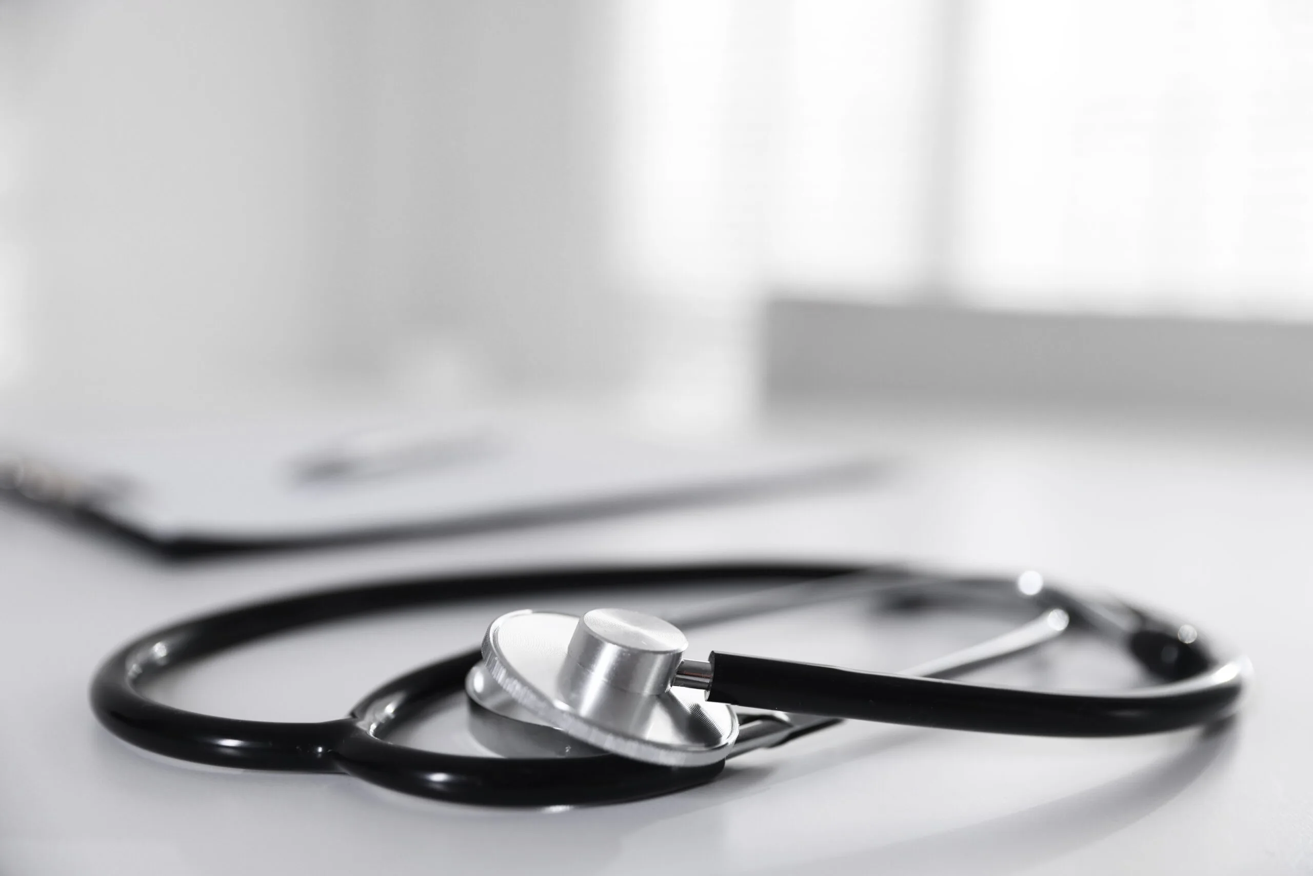Stethoscope and paperwork on a white desk.