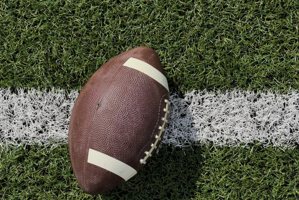 American football resting on a marked grass field.