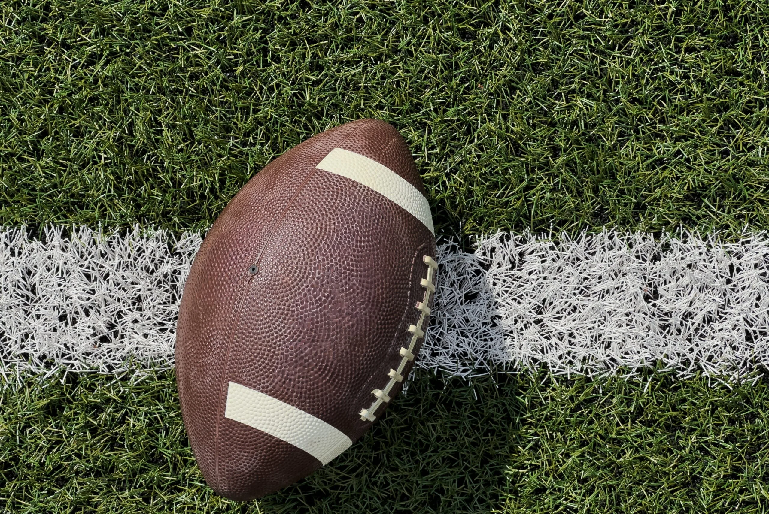 American football resting on a marked grass field.