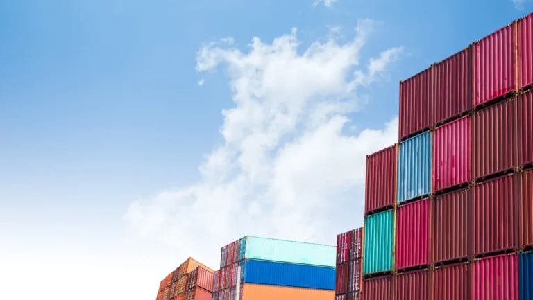 Stacked shipping containers beneath a blue sky.