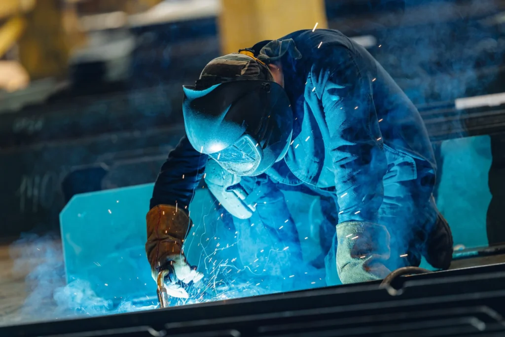 Welder working on metal while wearing protective equipment
