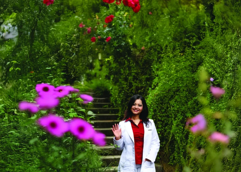Dr. Johnsy Pradhan, MD, smiling outdoors in a white coat.