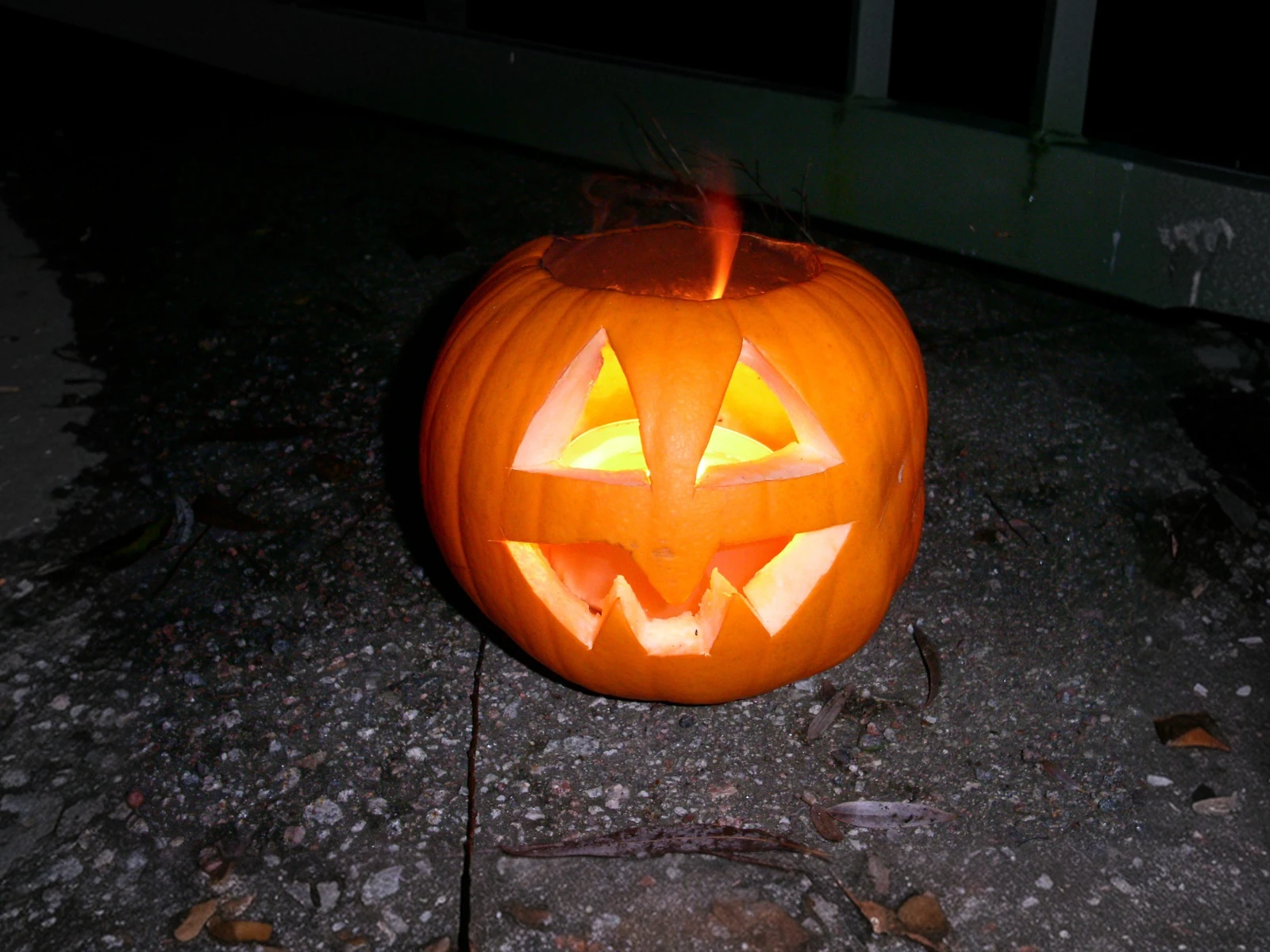 A carved Halloween pumpkin glowing on paving stones.