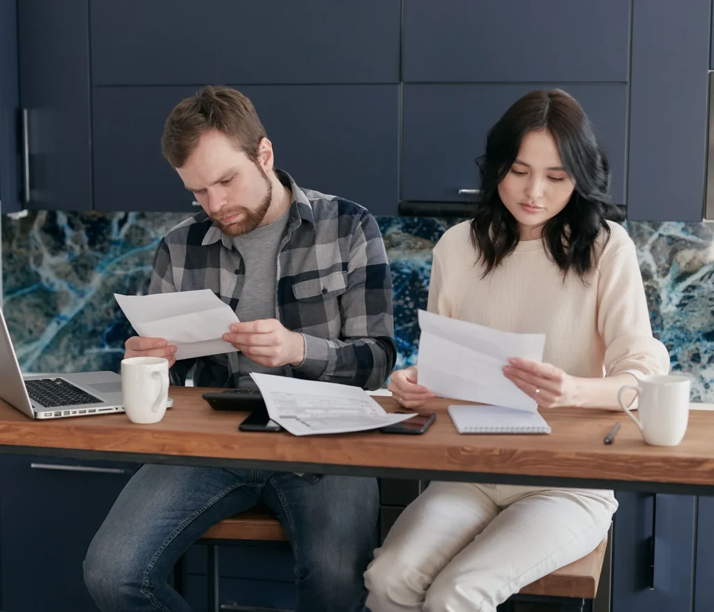 Two adults reviewing paperwork together at a kitchen counter.